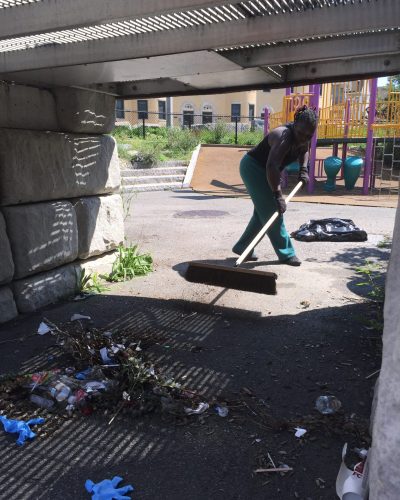 A woman sweeping the floor of an abandoned building.